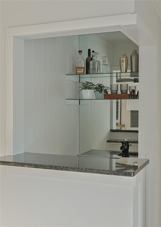 bar with dark stone countertops and stainless steel stovetop