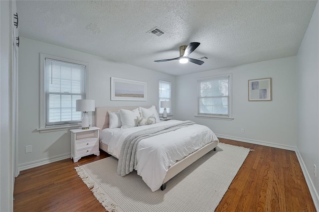 bedroom featuring ceiling fan, dark wood-type flooring, and a textured ceiling