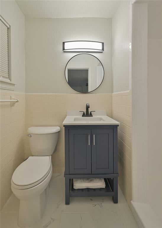 bathroom featuring vanity, toilet, and tile walls