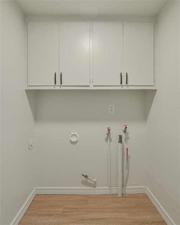 laundry room with cabinets, light wood-type flooring, hookup for a gas dryer, and hookup for an electric dryer