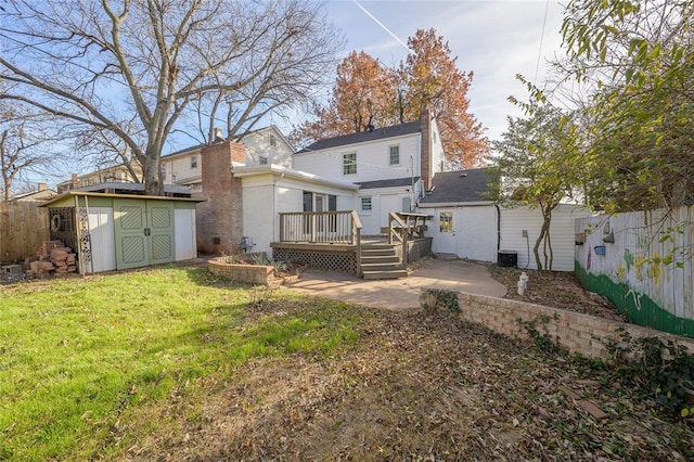 rear view of property with a lawn, a wooden deck, a patio area, and a storage shed