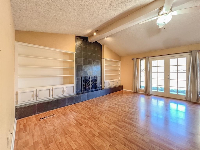 unfurnished living room featuring hardwood / wood-style floors, french doors, vaulted ceiling with beams, ceiling fan, and a textured ceiling