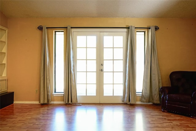 entryway featuring light wood-type flooring, a textured ceiling, a wealth of natural light, and french doors