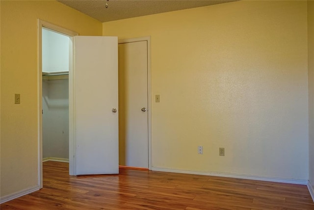 unfurnished bedroom featuring wood-type flooring, a textured ceiling, and a closet