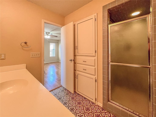 bathroom with an enclosed shower, a textured ceiling, ceiling fan, sink, and hardwood / wood-style floors