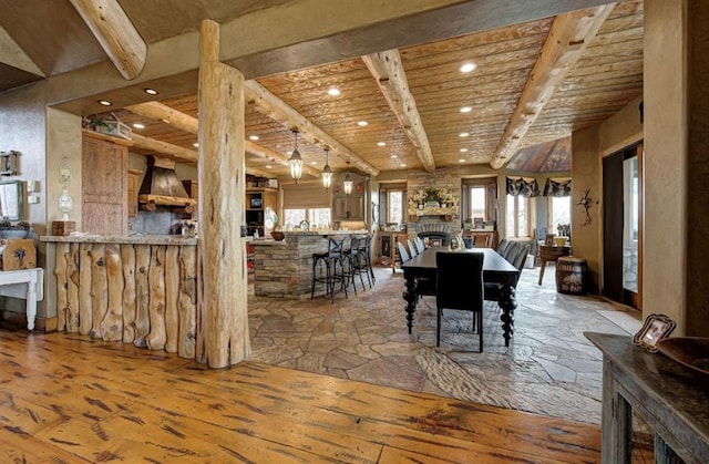 dining room with wood-type flooring, a stone fireplace, wooden ceiling, and beam ceiling