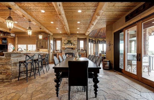 dining space with beam ceiling, wooden ceiling, a fireplace, and french doors