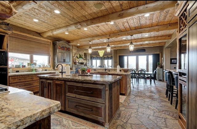 kitchen featuring a large island, sink, a healthy amount of sunlight, and decorative light fixtures