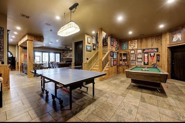 game room featuring pool table, a stone fireplace, ceiling fan, and wood walls