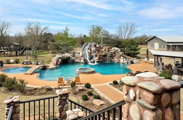 view of swimming pool with a patio area, an in ground hot tub, pool water feature, and a water slide