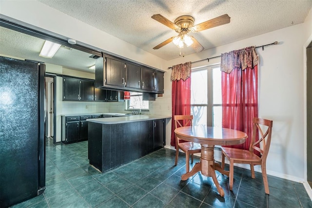 kitchen with sink, black refrigerator, kitchen peninsula, ceiling fan, and decorative backsplash