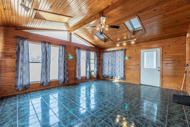 unfurnished room with ceiling fan, wooden walls, lofted ceiling with skylight, and wooden ceiling