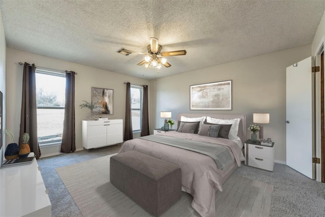 bedroom with ceiling fan, light colored carpet, and a textured ceiling