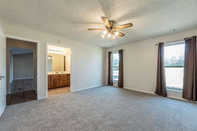 unfurnished bedroom with multiple windows, ensuite bath, and light carpet