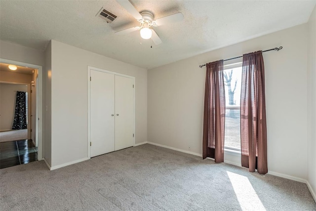 unfurnished bedroom featuring ceiling fan, light colored carpet, a closet, and a textured ceiling