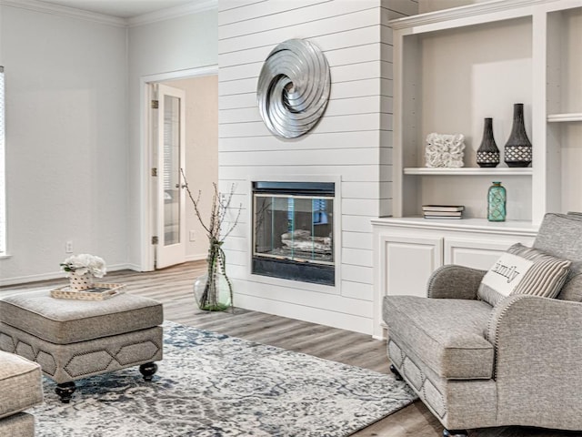 living room featuring a large fireplace, wood-type flooring, and ornamental molding