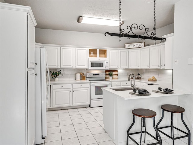 kitchen with white cabinets, decorative backsplash, white appliances, and sink