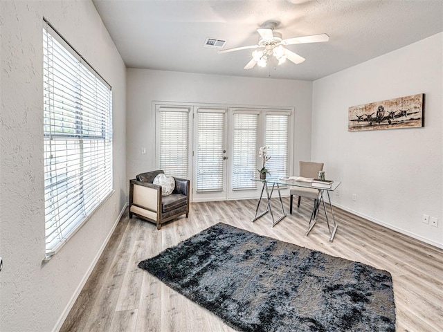 sitting room featuring ceiling fan, french doors, a healthy amount of sunlight, and wood-type flooring