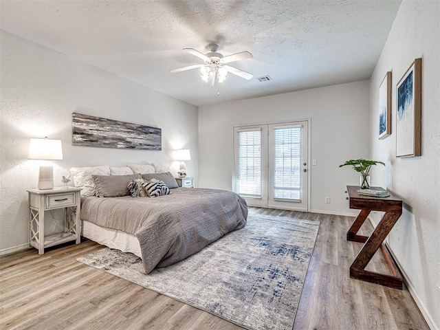 bedroom with hardwood / wood-style floors, a textured ceiling, access to outside, and ceiling fan