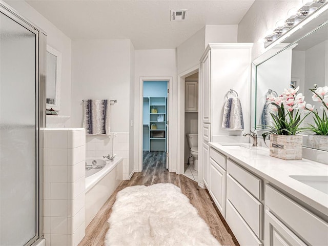 full bathroom with hardwood / wood-style flooring, vanity, separate shower and tub, and toilet