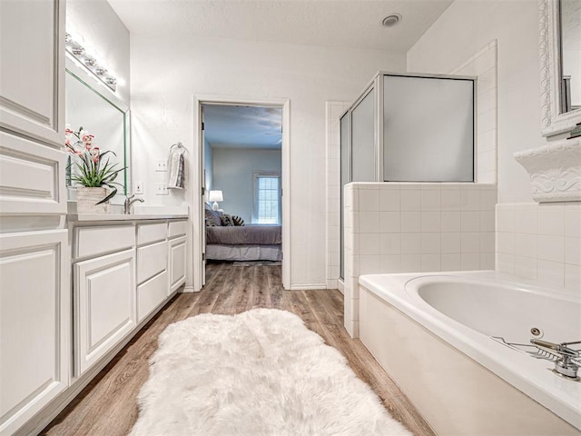 bathroom with shower with separate bathtub, vanity, and hardwood / wood-style flooring