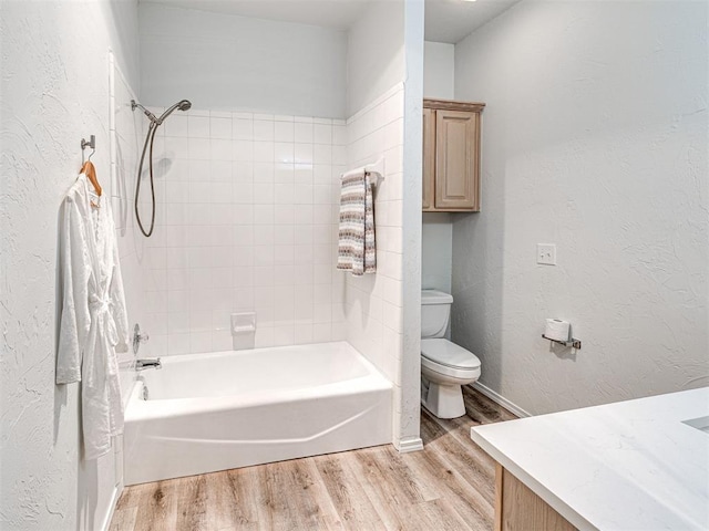 full bathroom with toilet, vanity, wood-type flooring, and tiled shower / bath