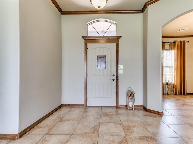 foyer entrance with crown molding and light tile patterned floors