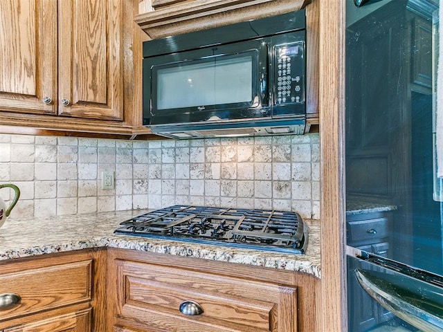 kitchen featuring tasteful backsplash, gas cooktop, and light stone counters