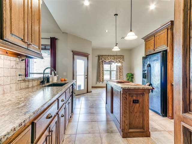 kitchen featuring sink, tasteful backsplash, decorative light fixtures, a kitchen island, and black appliances