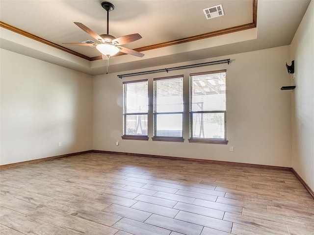 unfurnished room featuring crown molding, light hardwood / wood-style floors, a raised ceiling, and ceiling fan