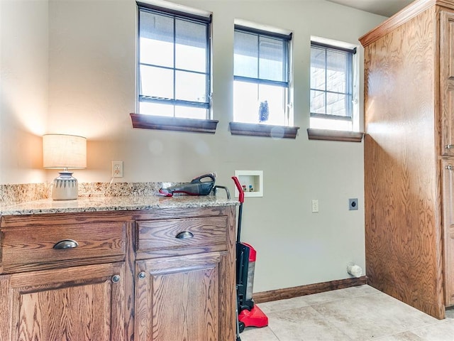 interior space with hookup for a washing machine, light tile patterned flooring, electric dryer hookup, and cabinets