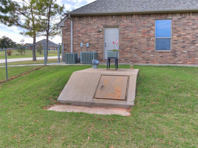 entry to storm shelter featuring a lawn and central air condition unit