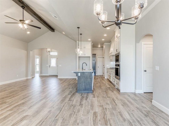 kitchen featuring pendant lighting, a kitchen island with sink, ceiling fan with notable chandelier, light wood-type flooring, and white cabinetry