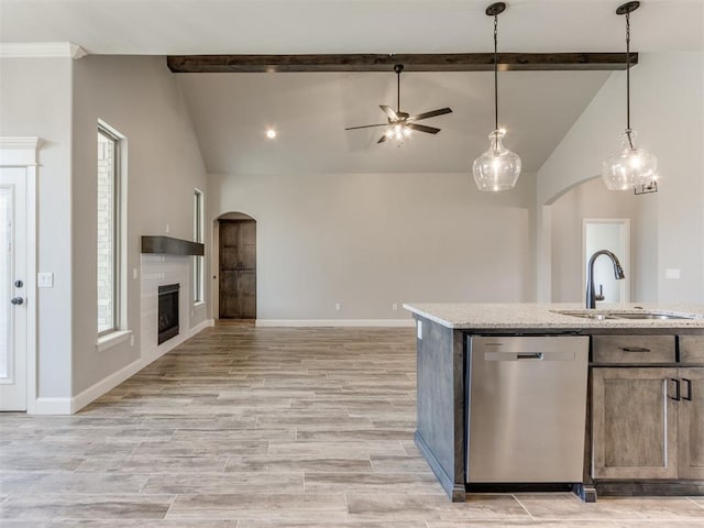 kitchen featuring sink, lofted ceiling with beams, dishwasher, light hardwood / wood-style floors, and a tiled fireplace