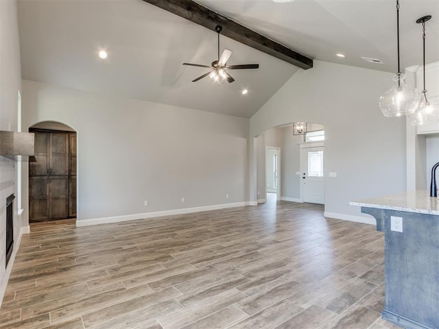 unfurnished living room featuring beam ceiling, ceiling fan, light hardwood / wood-style flooring, and high vaulted ceiling