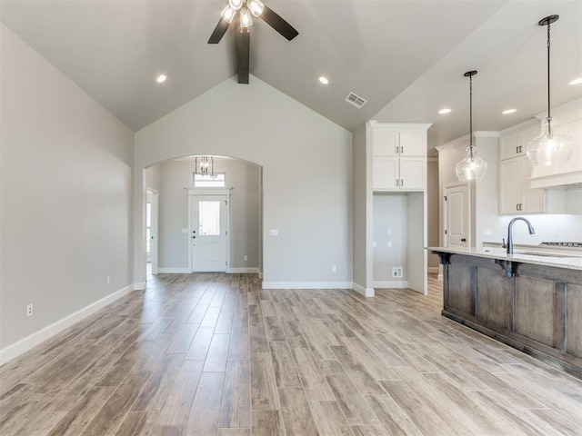 kitchen with light wood-type flooring, ceiling fan, pendant lighting, beam ceiling, and white cabinetry