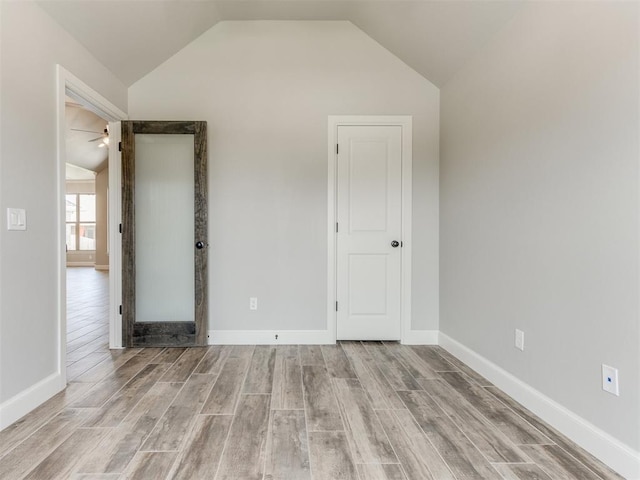 unfurnished bedroom with light wood-type flooring and vaulted ceiling