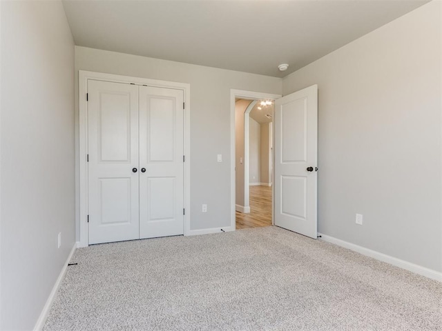 unfurnished bedroom with light carpet and a closet