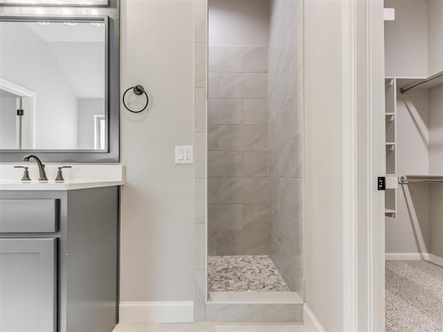 bathroom featuring tiled shower and vanity