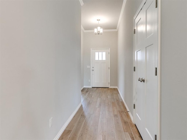 entryway featuring light wood-type flooring, crown molding, and a chandelier