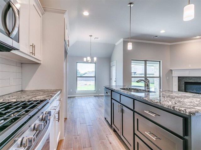 kitchen with white cabinets, plenty of natural light, light stone counters, and appliances with stainless steel finishes