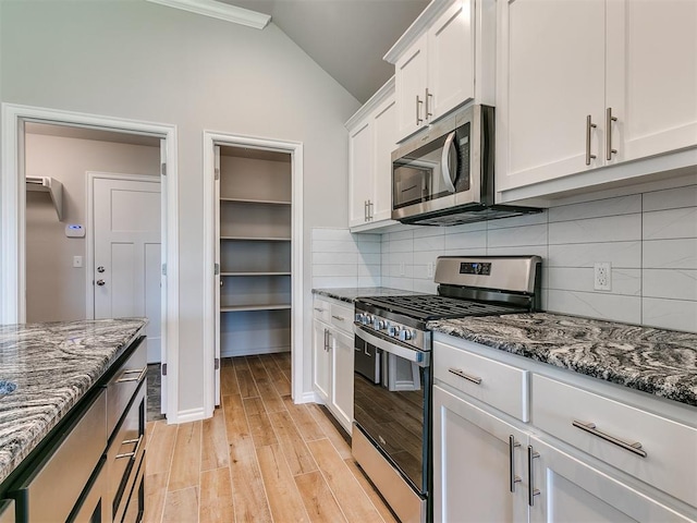 kitchen featuring white cabinetry, backsplash, vaulted ceiling, appliances with stainless steel finishes, and light wood-type flooring