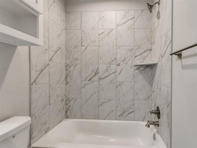 bathroom featuring toilet and tiled shower / bath