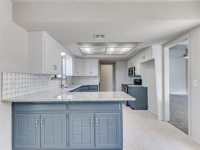 kitchen featuring sink, light carpet, kitchen peninsula, decorative backsplash, and white cabinets