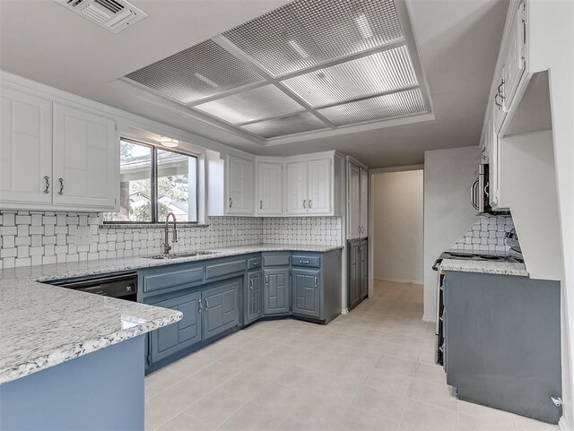 kitchen with light tile patterned floors, backsplash, white cabinetry, and sink