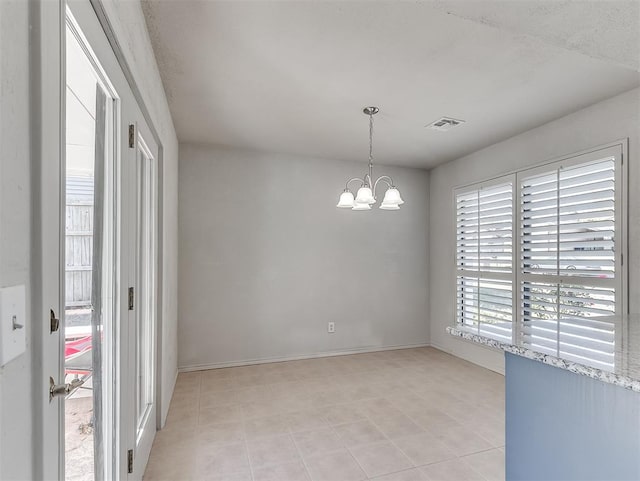 tiled empty room with an inviting chandelier