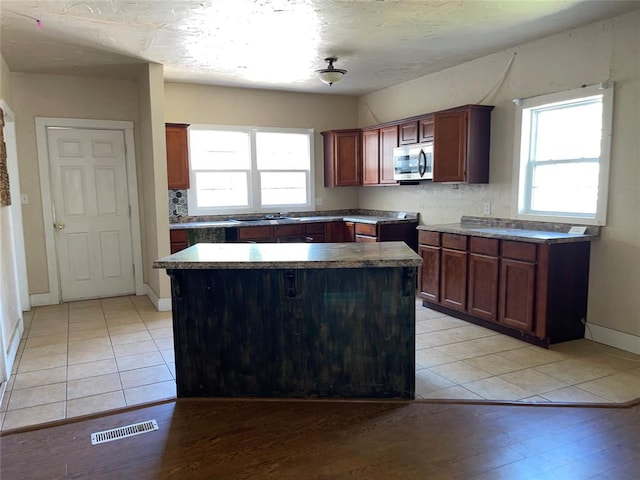 kitchen with light hardwood / wood-style floors, a kitchen island, and tasteful backsplash