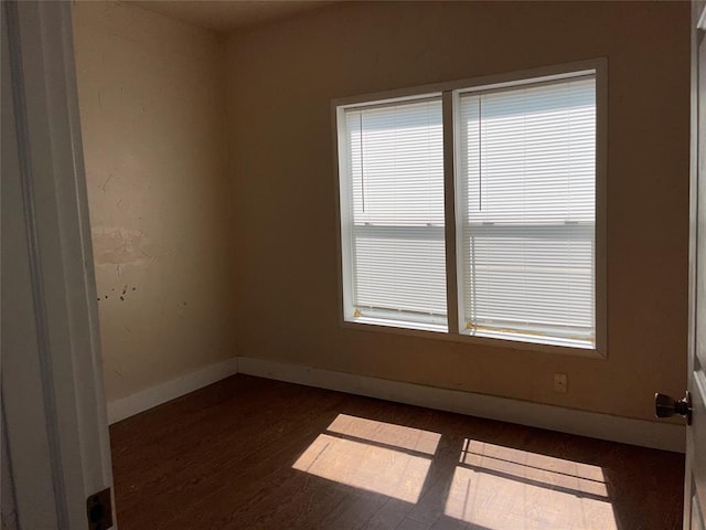 empty room with plenty of natural light and dark hardwood / wood-style floors