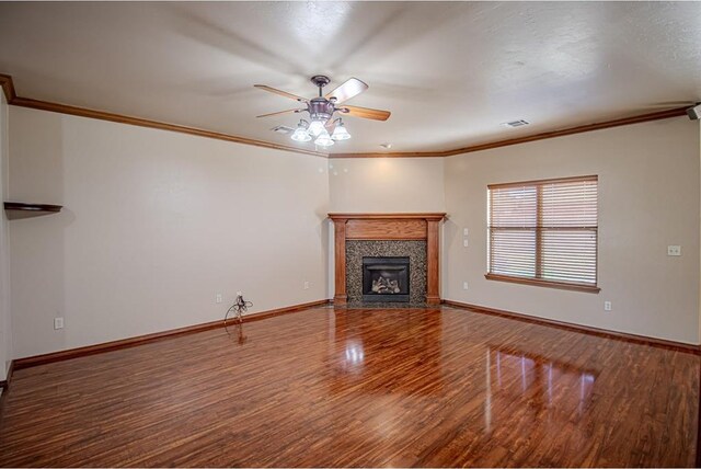 unfurnished living room featuring a high end fireplace, hardwood / wood-style floors, ceiling fan, and crown molding