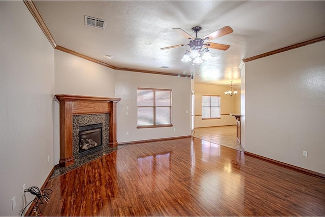 unfurnished living room featuring ornamental molding, ceiling fan with notable chandelier, a textured ceiling, hardwood / wood-style floors, and a tiled fireplace